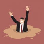 Businessman Sinking In A Puddle Of Quicksand Stock Photo