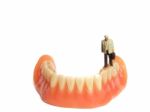 Miniature Elderly Standing On Removable Denture, On White Background. Dental Health Concept Stock Photo