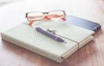 Notebook And Pen With Eyeglasses On Wooden Table Stock Photo