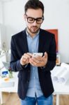 Handsome Young Man Using His Mobile Phone In The Office Stock Photo