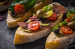 Slices Of Ciabatta With Olives , Tomatoes And Basil On The Black Stone Table Horizontal Stock Photo