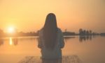 Silhouette Of Relaxing Young Woman On Wooden Pier At The Lake In Sunset Stock Photo