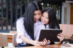 Two Asia Thai High School Student Uniform Best Friends Beautiful Girl Using Her Tablet And Funny Stock Photo