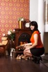 Young Beautiful Woman Sits Near The Fireplace Stock Photo