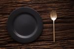 Black Empty Plate Fork Spoon On Wooden Table Background Stock Photo