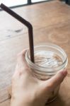 Hand On Iced Glass Of Latte Coffee Stock Photo