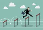 Businessman Jumping Higher Over Hurdle Stock Photo