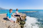 Mother And Son As Tourists Sitting On Rock At Blue Sea Stock Photo