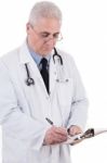 Portrait Of Senior Doctor Writing Reports Stock Photo