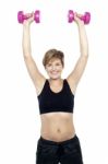 Mid Adult Woman Holding Dumbbells Over Head Stock Photo