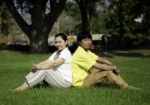 Portrait Of Beautiful Couple Sitting On Ground In Park Stock Photo