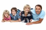 Smiling Family Of Four Relaxing On White Background Stock Photo