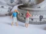 Miniature Woman Standing Near Measuring Tape, Thinking Of Weight Stock Photo