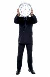 Executive Holding Up Wall Clock In Front Of His Face Stock Photo