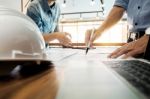 Architects Engineer Discussing At The Table With Blueprint - Clo Stock Photo