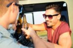 Portrait Of Two Friends Toasting With Bottles Of Beer In Car Stock Photo