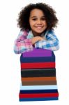 Smart Little Girl Leaning Over Pile Of Books Stock Photo