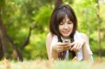 Lady Lying In Park With Phone Stock Photo