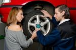 Auto Mechanic And Female Trainee Changing A Car Tyre In Garage Stock Photo