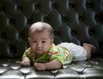 Baby Lying On Sofa Bed With Eyes Contact To Camera Stock Photo