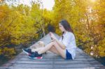 Girl Sitting Alone And Hand Holding Camera On A The Wooden Bridge In Autumn. Vintage Tone Stock Photo