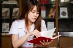 Portrait Of Thai Adult Student University Uniform Beautiful Girl Reading Red Book Stock Photo