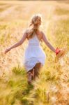 Happy Young Blonde Girl In White Dress With Straw Hat Running Th Stock Photo