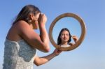 Woman Applying Mascara Makeup In Mirror With Sky Stock Photo