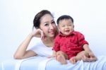 Portrait Of Laughing Asian Mother And Sitting Baby On Bench Stock Photo