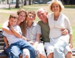 Happy Family Sitting On Park Bench Stock Photo