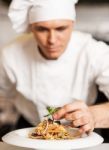 Chef Decorating Pasta Salad With Herbal Leaves Stock Photo