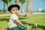 The Thai Kid Sits On The Grass Stock Photo