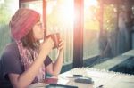 Asian Younger Woman And Hot Coffee Mug In Hand Smiling With Happiness Emotion Sitting Beside Mirror Window Against Beautiful Sun Light ,process Warming Color Mood And Tone Stock Photo