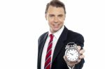 Smiling Young Consultant Showing Alarm Clock Stock Photo