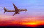 Commercial Airplane Flying At Sunset Stock Photo