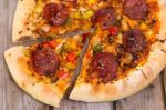 Delicious Baked Salami Pizza Served On Rustic Wooden Table Stock Photo