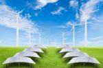 Solar Panels And Wind Turbine On Green Grass Field Against Blue Stock Photo