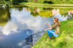 Young Dutch Woman At Waterside With Fishing Rod And Net Stock Photo