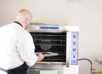 Chef Putting A Tray Of A Juicy Steak In A Professional Oven Stock Photo