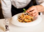 Chef Decorating Pasta Salad With Herbal Leaves Stock Photo