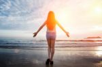 Beautiful Girl Walking On The Beach At Sunset Stock Photo