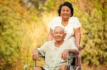 Senior Woman Pushing Her Disabled Hasband On Wheelchair Stock Photo