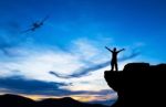 Silhouette Of A Man On The Rock And Silhouette Commercial Plane Stock Photo