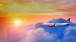 Airplane Flying Above Clouds In Sunset Light Stock Photo