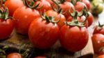 Cherry Tomatoes On Display On Wooden Chopping Board And Wooden Table Stock Photo