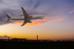 Commercial Airplane Flying Over The Airport At Sunset Stock Photo