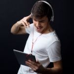 Young Beautiful Man Listening To Music. Isolated On Black Stock Photo