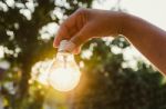 And Holding A Light Bulb With Sunset Power Concept Stock Photo