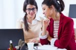 Two Young Businesswomen Working With Laptop In Her Office Stock Photo