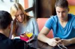 Group Of Friends Using Mobile Phone In Cafe Stock Photo